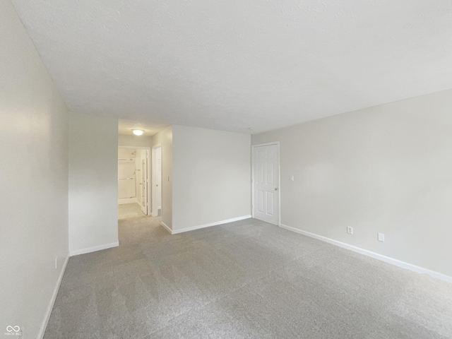 spare room featuring light carpet and a textured ceiling