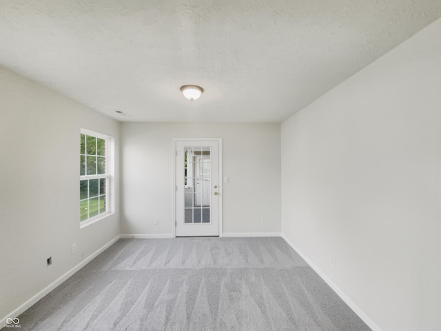 unfurnished room with light colored carpet and a textured ceiling