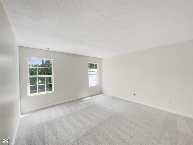 empty room with light colored carpet and a textured ceiling