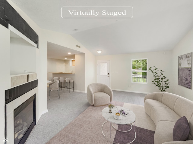 carpeted living room featuring vaulted ceiling and a tile fireplace