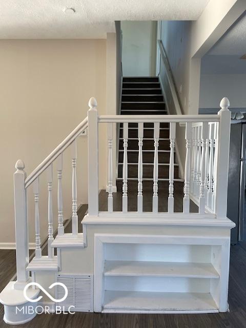 staircase featuring wood-type flooring and a textured ceiling