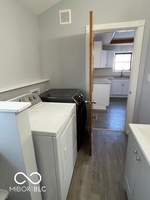 washroom with separate washer and dryer, sink, dark wood-type flooring, and a textured ceiling