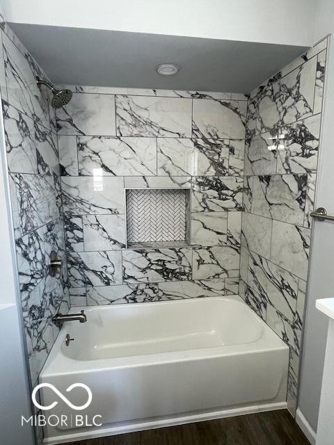 bathroom with hardwood / wood-style floors and tiled shower / bath