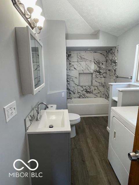 full bathroom featuring hardwood / wood-style flooring, vanity, a textured ceiling, and washer / clothes dryer