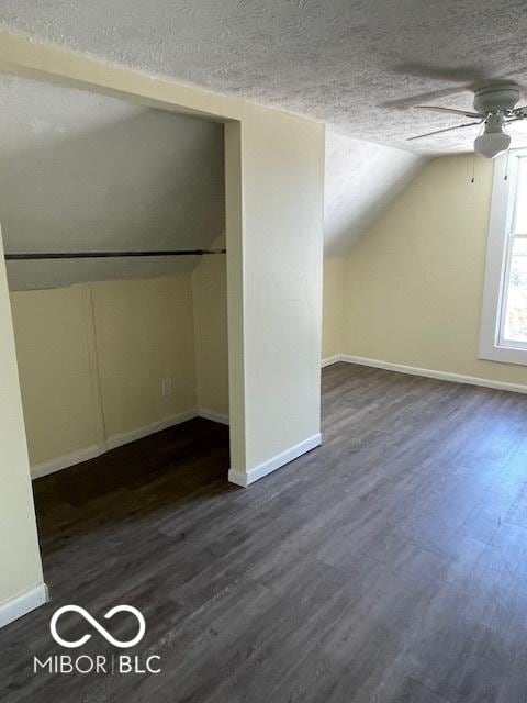 additional living space featuring a textured ceiling, ceiling fan, dark wood-type flooring, and lofted ceiling