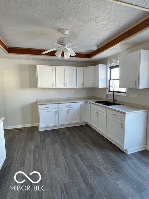 kitchen with white cabinets, sink, a textured ceiling, a tray ceiling, and dark hardwood / wood-style flooring