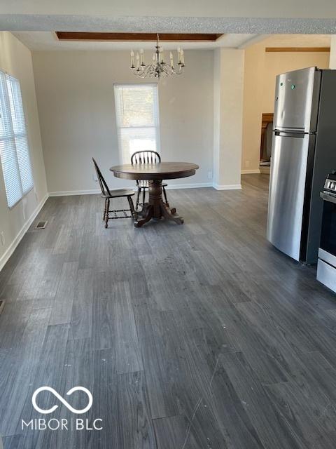 unfurnished dining area featuring dark hardwood / wood-style flooring, an inviting chandelier, and a wealth of natural light