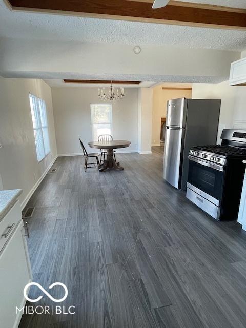 kitchen featuring a textured ceiling, ceiling fan with notable chandelier, stainless steel appliances, white cabinets, and dark hardwood / wood-style floors