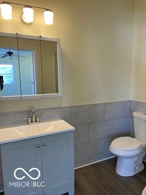 bathroom featuring vanity, ceiling fan, tile walls, hardwood / wood-style floors, and toilet