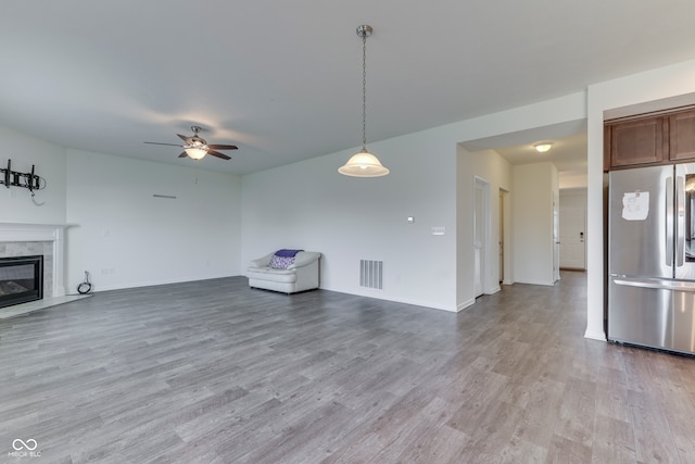 unfurnished living room featuring ceiling fan, light wood-type flooring, and a fireplace