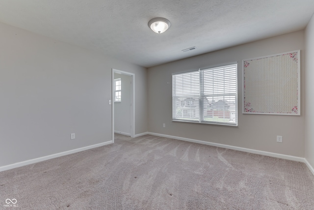 carpeted empty room featuring a textured ceiling