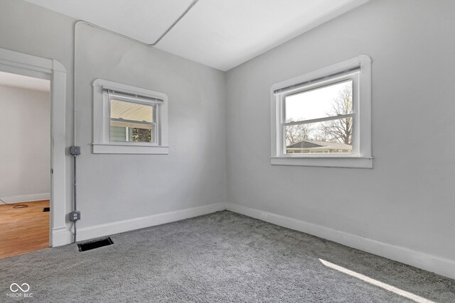 empty room with a healthy amount of sunlight, baseboards, visible vents, and carpet floors