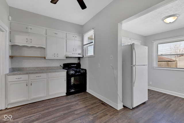 kitchen with under cabinet range hood, freestanding refrigerator, baseboards, and black gas range oven