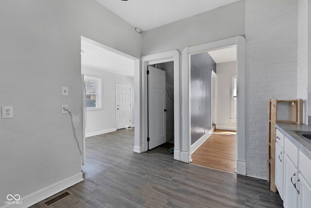 hallway with visible vents, baseboards, and dark wood finished floors
