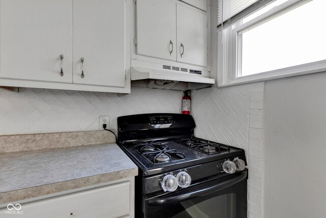 kitchen featuring gas stove, white cabinetry, light countertops, backsplash, and under cabinet range hood