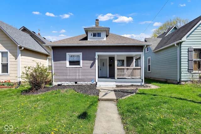 bungalow featuring roof with shingles, a front yard, a porch, and a chimney