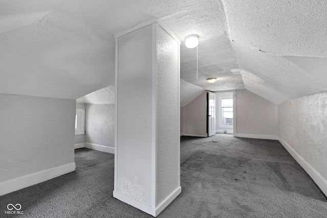 additional living space featuring baseboards, carpet flooring, vaulted ceiling, and a textured ceiling