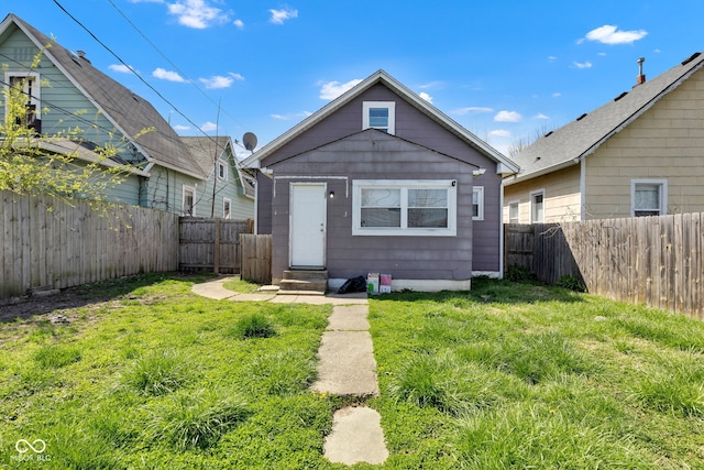 view of front of home featuring entry steps, a fenced backyard, and a front lawn