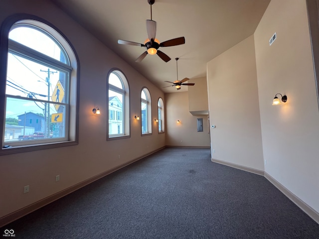 carpeted empty room featuring lofted ceiling, a healthy amount of sunlight, and ceiling fan