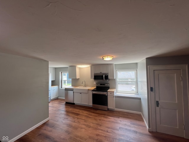 kitchen featuring sink, appliances with stainless steel finishes, hardwood / wood-style flooring, and white cabinetry