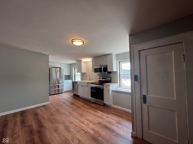 kitchen with sink, appliances with stainless steel finishes, light wood-type flooring, and white cabinets