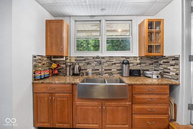 kitchen with decorative backsplash, light stone countertops, and sink