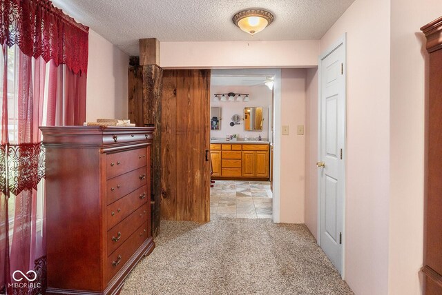 hall with a textured ceiling, light tile patterned floors, and plenty of natural light