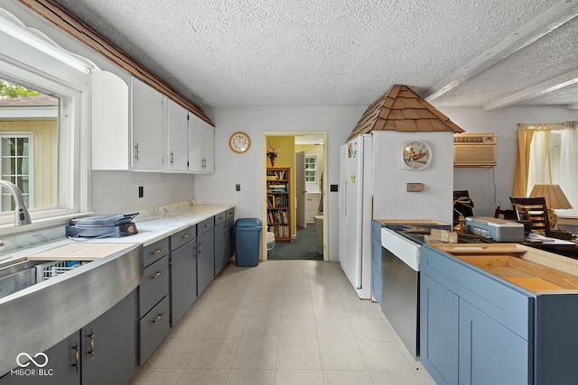 kitchen featuring white cabinets, a wall unit AC, light tile patterned floors, and a textured ceiling