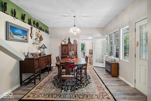 dining room featuring wood-type flooring, a notable chandelier, and a textured ceiling