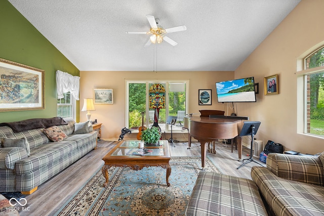 living room with a textured ceiling, vaulted ceiling, light hardwood / wood-style flooring, and ceiling fan