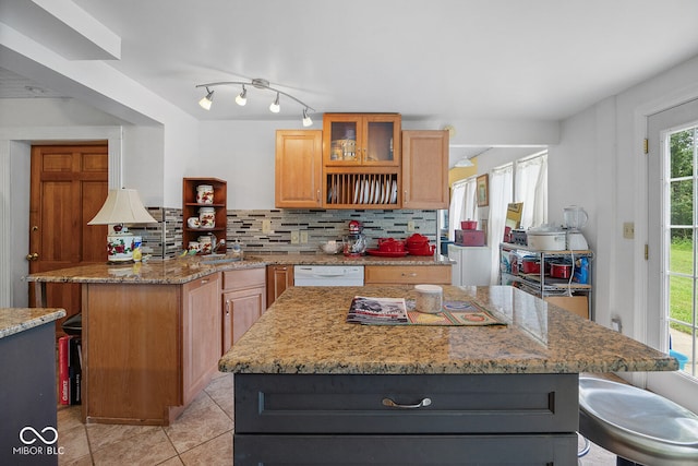 kitchen featuring a center island, light stone counters, dishwasher, and backsplash