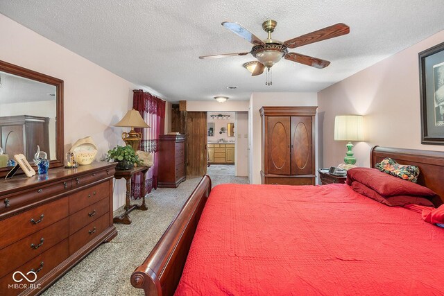 carpeted bedroom featuring ensuite bathroom, a textured ceiling, and ceiling fan