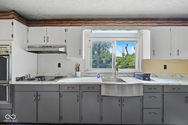 kitchen with range hood, cooktop, a textured ceiling, and gray cabinetry