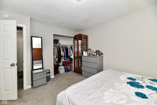 bedroom featuring a textured ceiling, a closet, baseboards, and light carpet