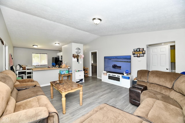 living area with baseboards, a textured ceiling, lofted ceiling, and wood finished floors