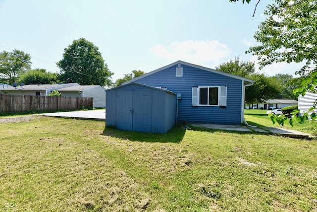 back of house with a yard, a shed, an outdoor structure, and fence