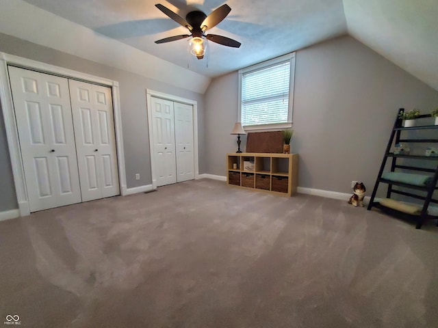 unfurnished bedroom featuring lofted ceiling, two closets, ceiling fan, and carpet flooring