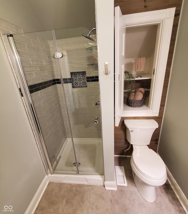 bathroom featuring toilet, a shower with door, and tile patterned flooring