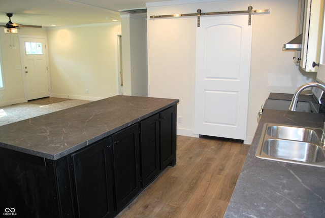 kitchen featuring extractor fan, dark stone countertops, hardwood / wood-style flooring, ceiling fan, and sink