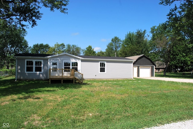 view of front of property featuring a garage, a front lawn, a deck, and an outbuilding