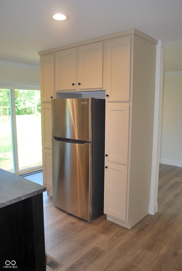 kitchen with stone countertops, light hardwood / wood-style flooring, white cabinetry, and stainless steel refrigerator