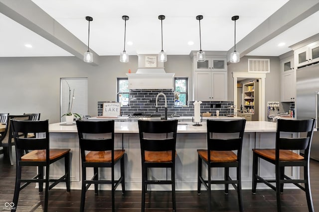 kitchen with a kitchen breakfast bar, dark hardwood / wood-style floors, pendant lighting, tasteful backsplash, and custom exhaust hood