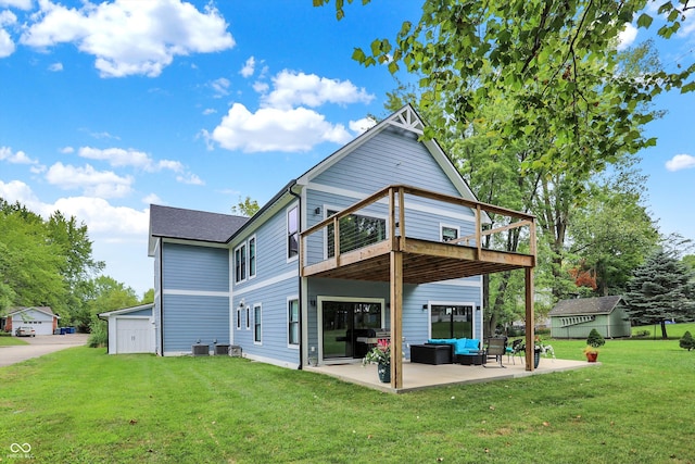 back of house with a deck, a yard, an outdoor living space, an outbuilding, and a patio