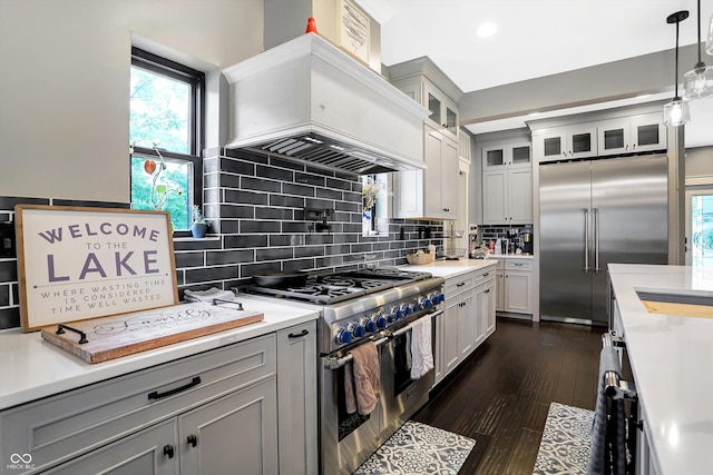 kitchen with custom range hood, tasteful backsplash, pendant lighting, dark hardwood / wood-style flooring, and high end appliances