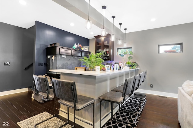 bar featuring pendant lighting, dark hardwood / wood-style flooring, and dark brown cabinets