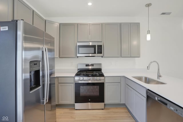 kitchen with pendant lighting, sink, gray cabinets, and stainless steel appliances