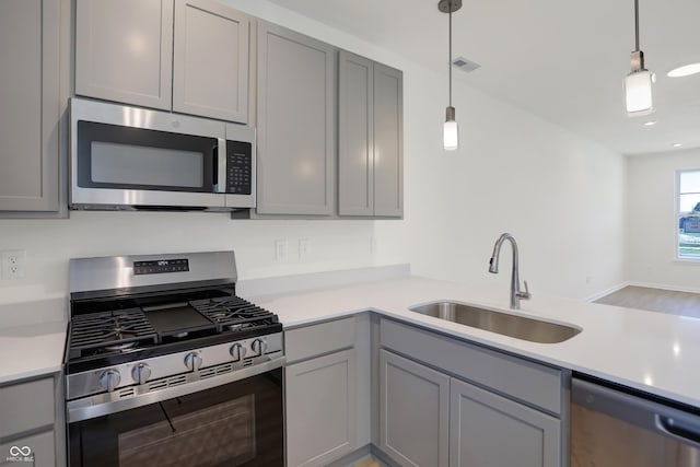 kitchen featuring gray cabinets, sink, pendant lighting, and appliances with stainless steel finishes