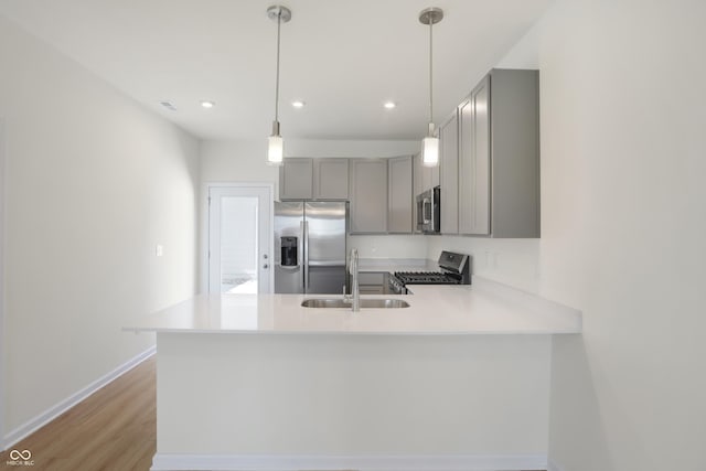 kitchen with kitchen peninsula, sink, decorative light fixtures, and appliances with stainless steel finishes