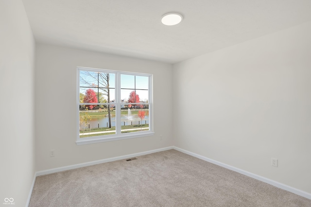 unfurnished room with a water view and light colored carpet