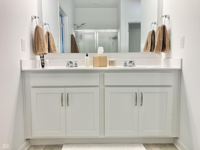 bathroom with a sink, a shower stall, baseboards, and double vanity